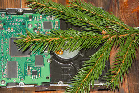 Computer hard drive with green branch Christmas tree on dark wooden table background. New Year and...
