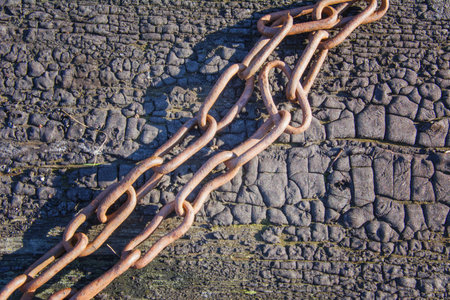 Old rusty chain on wooden surface covered with resin. The structure of black burnt wood.