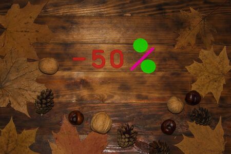 Autumn Sale 50 Percent Discount. The inscription on a dark wooden background in a frame of colorful autumn leaves. Top viewの写真素材