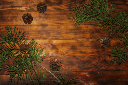 Christmas Fir tree green branches and pine cones on dark wooden rustic background. Xmas decoration...