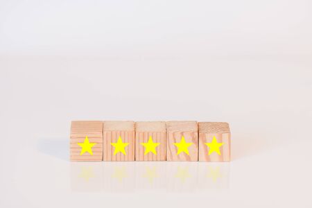 Five wooden cubes with the image of a yellow star on white background. The best excellent business services rating of company customer experience conceptの写真素材