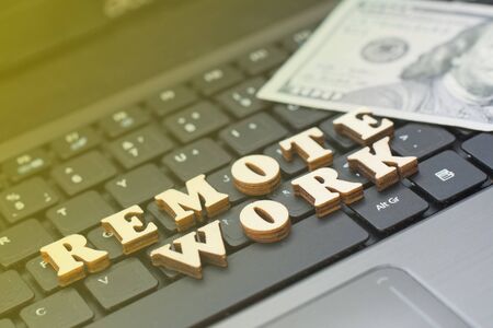 The inscription remote work against the background of a working laptop and money. The concept of working through the Internetの写真素材
