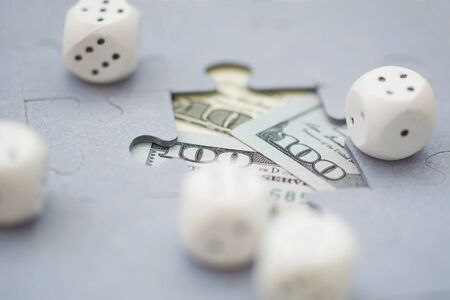 Rolling dice on Hundred dollar bills through the missing piece of jigsaw puzzles. Gambling concept.の写真素材