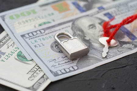 Closed padlock with key and money on wooden table. Business safety or financial protection or...