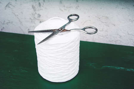 Old vintage scissors and skein jute twine on green table background. Rustic, wabi sabi needlework, hobby, sewing and tailoring.の写真素材