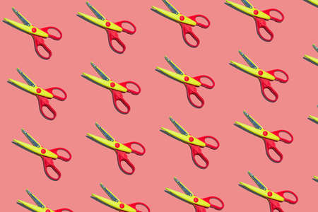 Open plastic yellow and red scissors on pastel pink color background. Seamless colorful patternの写真素材