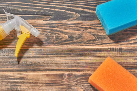 Cleaning spray plastic bottle and cleaning sponges on dark rustic wooden background. Flat lay, top view with copyspace. The concept of washing and cleaningの写真素材