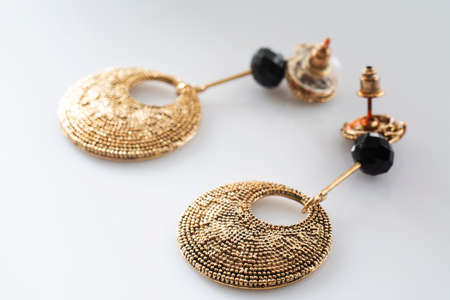Modern golden jewelry earrings on white background. Pair of jewelry on table. Selective soft focus, shallow depth of fieldの写真素材