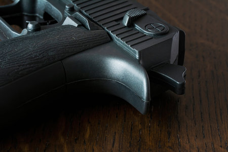 Black pistol on wooden background. Weapons for sport and self-defense on table. Handgun closeup view