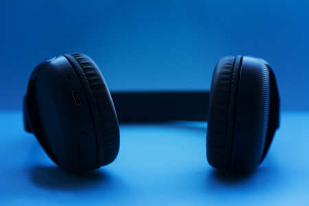 Wireless Headphones on blue background. Closeup view. Music concept. Shallow depth of field imageの写真素材