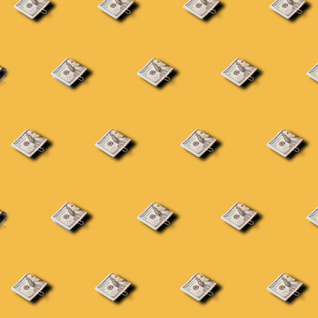 Creative pattern made 100 dollar bills on yellow background. Minimal financial business concept