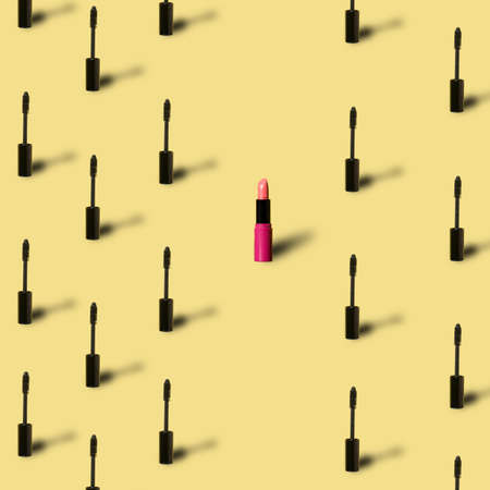 Minimal creative makeup cosmetic pattern. Many black mascara and one red lipstick with shadow on yellow background in pop art style. Beauty or cosmetic conceptの写真素材
