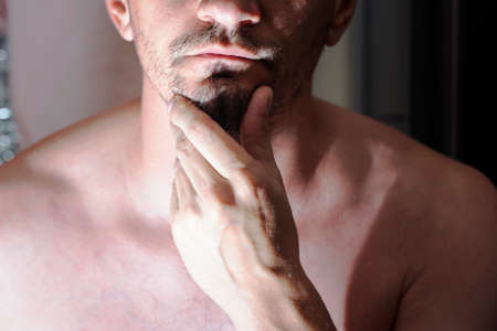 Portrait of young bearded caucasian man holds hand near his chin.の写真素材