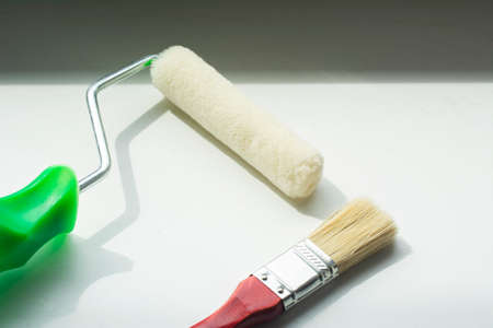 Foam roller and brush for painting on white background. Minimal construction conceptの写真素材