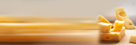 Panoramic banner. Maasdam Dutch cows milk cheese. Pieces of fresh yellow cheese, chunk on wooden...