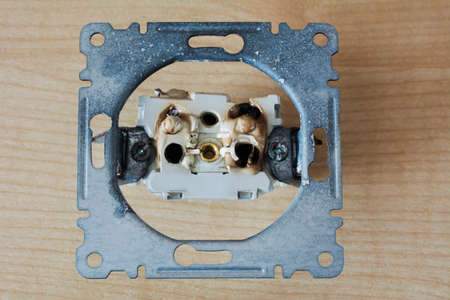 Broken power overload switch electric outlet. Electric short circuit causing fire on plug socket.の写真素材
