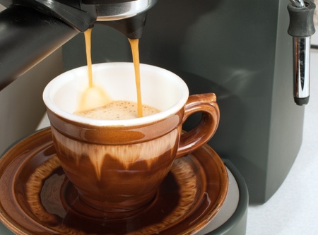 Coffee maker pouring hot espresso coffee in  cupsの写真素材