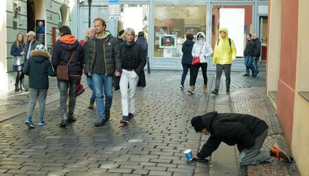PRAGUE, CZECH REPUBLIC, SEPTEMBER 9, 2019: Homeless begging tourists throw coin money into cup and recalculates money, begs alms kneeling or kneel street life authenticのeditorial素材