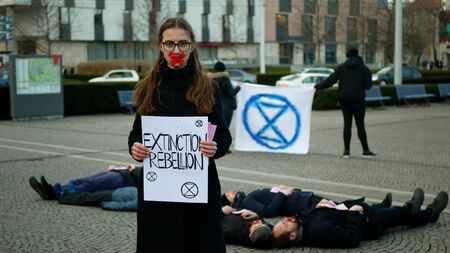 OLOMOUC, CZECH REPUBLIC, JANUARY 10, 2019: Extinction rebellion activist Anna Martinkova banner symbol circle hourglass warning, people lie on ground square showing death, demonstrationのeditorial素材