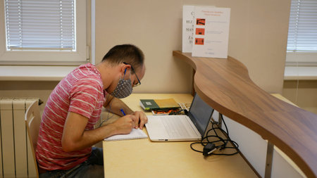 Coronavirus mask face student studying learning learn in university library on laptop and book...