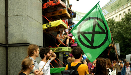 PRAGUE, CZECH REPUBLIC, JUNE 28, 2021: Demonstration Extinction Rebellion protest blocking block blockade Bank, flag symbol hourglass planet warning woman tied chained building climate activistのeditorial素材