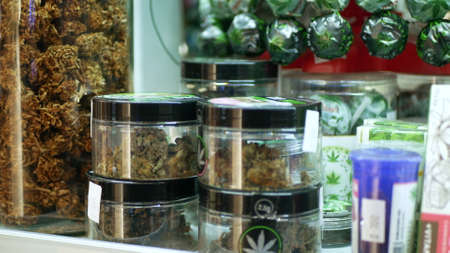 PRAGUE, CZECH REPUBLIC, SEPTEMBER 25, 2021: Cannabis bud dried shop medicinal hemp for smoking cigarettes joint harvested glass seeds sativa weed store, packaged hemp CBD, leaf symbolのeditorial素材