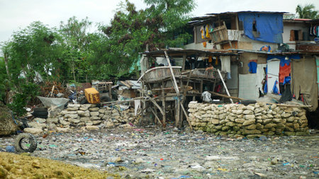Philippine slum poor waste shanty landfill coast sea waste pollution house densely populated people hungry people family Cebu trash village contamination garbage passing sea rubbish seashore cottageの写真素材
