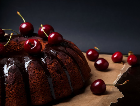 Delicious chocolate cake with glaze and cherries on the black backgroundの写真素材