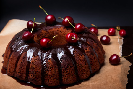 Delicious chocolate cake with glaze and cherries on the black backgroundの写真素材