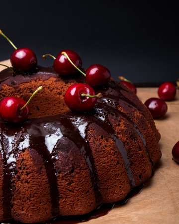 Delicious chocolate cake with glaze and cherries on the black backgroundの写真素材