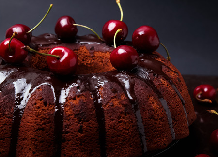 Delicious chocolate cake with glaze and cherries on the black background close upの写真素材