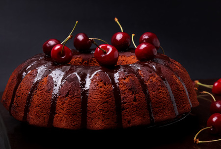 Delicious chocolate cake with glaze and cherries on the black backgroundの写真素材