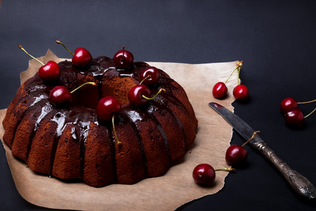 Delicious chocolate cake with glaze and cherries on the black backgroundの写真素材