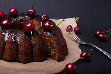 Delicious chocolate cake with glaze and cherries on the black backgroundの写真素材