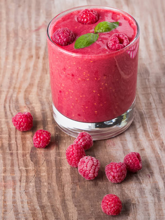 Raspberry smoothie in a glass on wooden tableの写真素材
