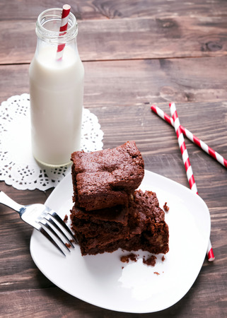 Brownies on the plate and milk in the bottle on the wooden tableの写真素材