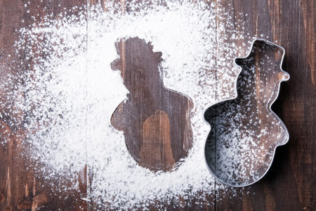Snowman cutter for cookies and flour on the wooden table
