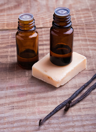 Bottles with aroma oil, vanilla pods and hand made soap on the wooden background. Spa stipp life.の写真素材