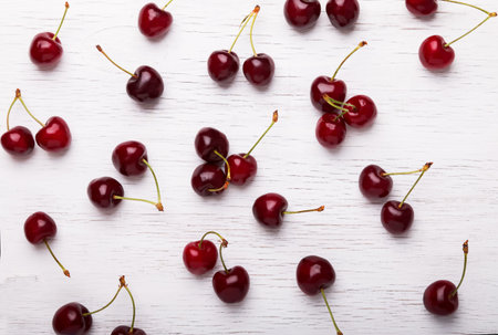 Fresh juicy cherries on the white wooden background, top view