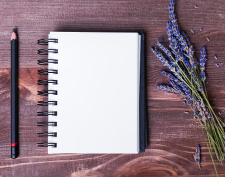 Lavender flowers, empty notepad and pensil on wooden table, top view