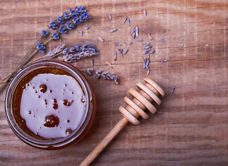 Honey in a glass jar, honey spoon and lavender flowers on the wooden table, top viewの写真素材