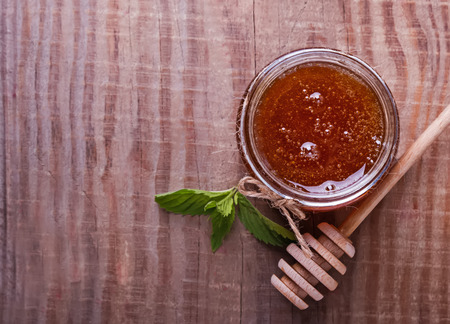Honey in a glass jar and honey spoon on the wooden table, top viewの写真素材