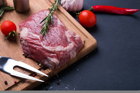 Raw beef steak and spices on the wooden board close-upの写真素材