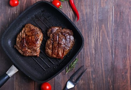 Roasted beef steaks in the pan on the wooden table, top view.の写真素材