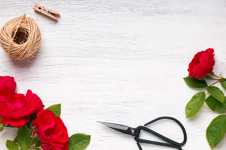 Red roses, jute rope and scissors on the white wooden table, top viewの写真素材