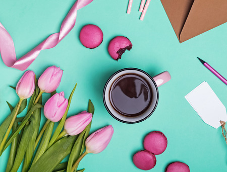 Spring items on pastel green background. Tulips, macarons, ribbon and coffee in pink mugの写真素材