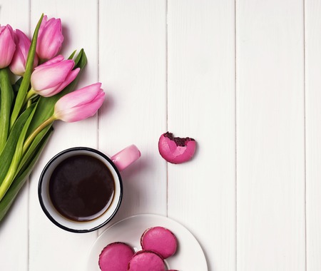 Coffee, pink tulips and macarons on the white wooden tableの写真素材