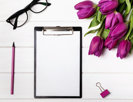 Mock up with blank paper, tulips and pink accessories. Workplace top view.の写真素材
