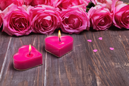 Two burning candles and beautiful pink roses on the wooden background. Valentine's day conceptの写真素材