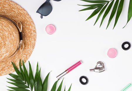 Summer feminine accessories and green leaves on the white background, top viewの写真素材